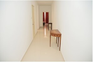 A narrow hallway with a wooden table and a door at the end.