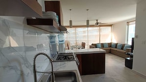 A modern kitchen with a central island, a dining area with a sofa, and a TV.