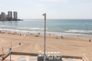 A beach with people, a lifeguard tower, and buildings in the background.