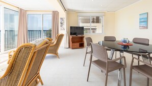 A room with a balcony, a TV, a dining table with chairs, and a sofa. - ApartUP Acapulco Beachfront Views (Oropesa del Mar)