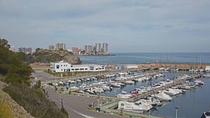 A marina with numerous boats docked, a parking area, and a building with a blue door. - ApartUP Acapulco Beachfront Views (Oropesa del Mar)
