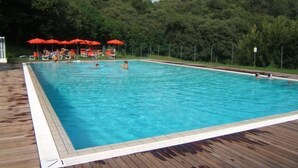 A rectangular swimming pool with a wooden deck surrounding it.