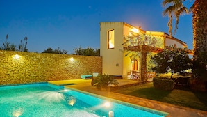 A swimming pool with a stone wall and a small building with a balcony. - Villa with splendid pool near the beaches, 4 bedrooms (Marinella di Selinunte)