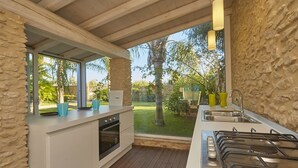 A modern kitchen with a stone wall, wooden ceiling, and a view of the garden. - Villa with splendid pool near the beaches, 4 bedrooms (Marinella di Selinunte)