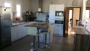 Cocina moderna con electrodomésticos de acero inoxidable, una isla central con taburetes y un microondas sobre el horno.