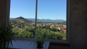 Una habitación con un ventanal que ofrece vistas a un pueblo y montañas.