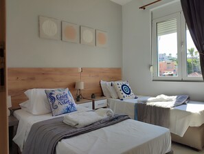 Une chambre d’hôtel avec deux lits, une tête de lit en bois, une fenêtre avec des rideaux et des œuvres d’art murales.