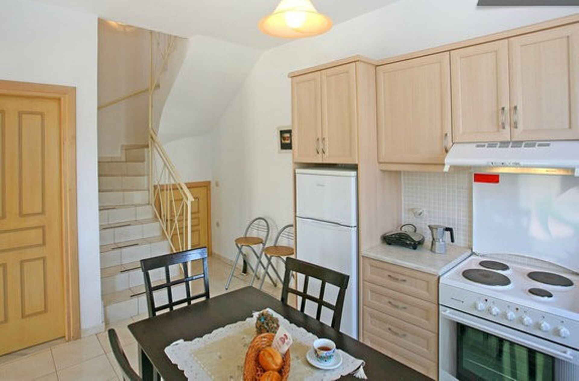 Une cuisine avec des meubles de rangement en bois, un réfrigérateur, une cuisinière et une table à manger avec des chaises.