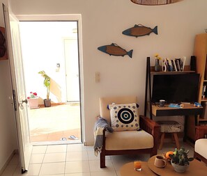 A living room with a sofa, a coffee table, a bookshelf, and a television.