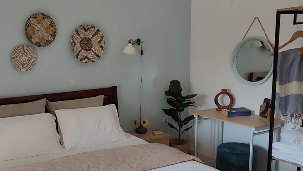 A neatly arranged bedroom with a bed, bedside tables, a desk, a mirror, and wall decorations.