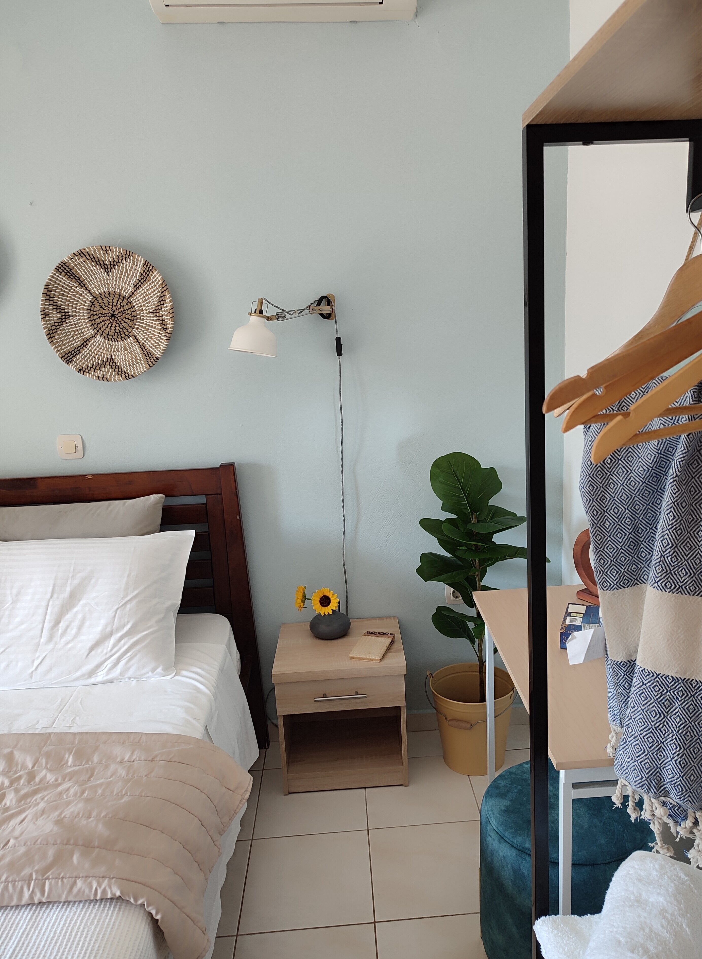 A bedroom with a bed, bedside table, lamp, wall decor, and a mirror.