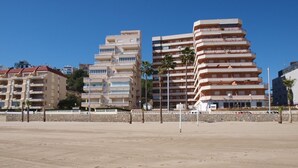 A beachfront hotel with multiple floors, balconies, and a sandy beach in the foreground. - ApartUP La Concha Beachfront I (Oropesa del Mar)