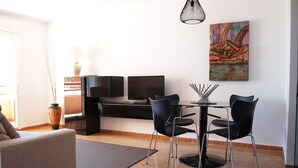 A modern living room with a sofa, a dining table with chairs, a TV, and artwork on the wall. - ApartUP La Concha Beachfront I (Oropesa del Mar)