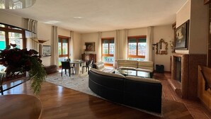 A spacious living room with a curved sofa, a dining table, and a fireplace.
