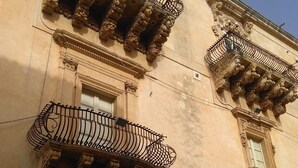 Ein Gebäude mit aufwendigen Balkonen, rundbogigen Fenstern und einer verwitterten Fassade.