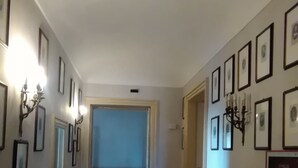 Ein Flur mit gerahmten Bildern an den Wänden, einem roten Teppich und einer Tür zu einem anderen Raum.