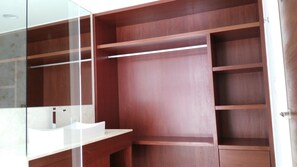 A walk-in closet with multiple wooden shelves and a white vanity with a sink.