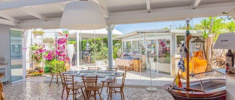 A restaurant with a glass enclosure, outdoor seating, and a ship model.