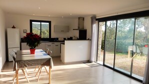 A modern kitchen with a dining area, large windows, and a view of greenery. - Superb villa in Porto-vecchio  (Porto-Vecchio)