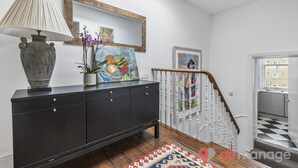 A hallway with a dark wooden console table, a lamp, and a colorful painting.