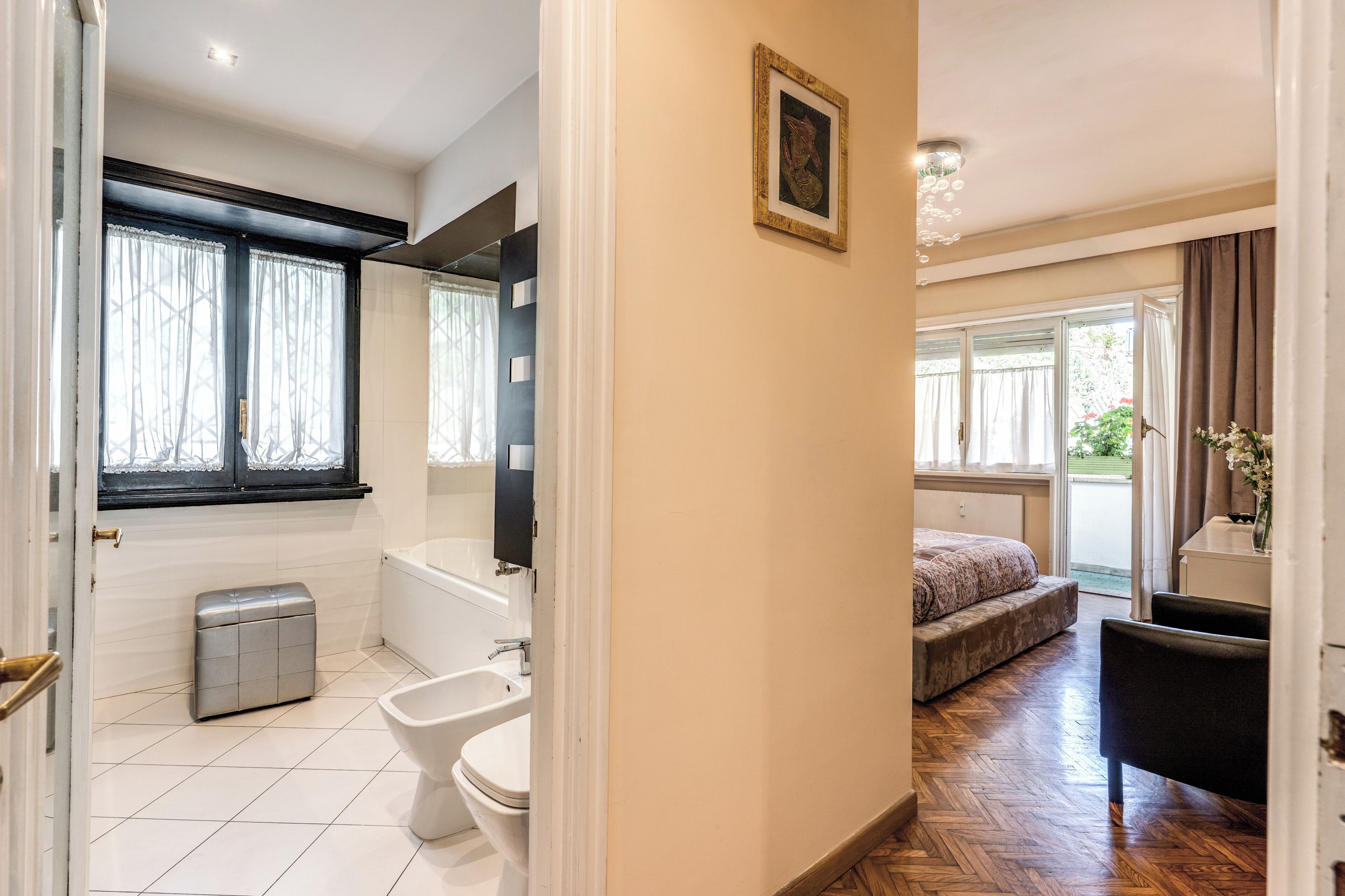 A bathroom with a toilet, bidet, and bathtub, a bedroom with a bed and chair, and a hallway with a door leading to the bathroom.