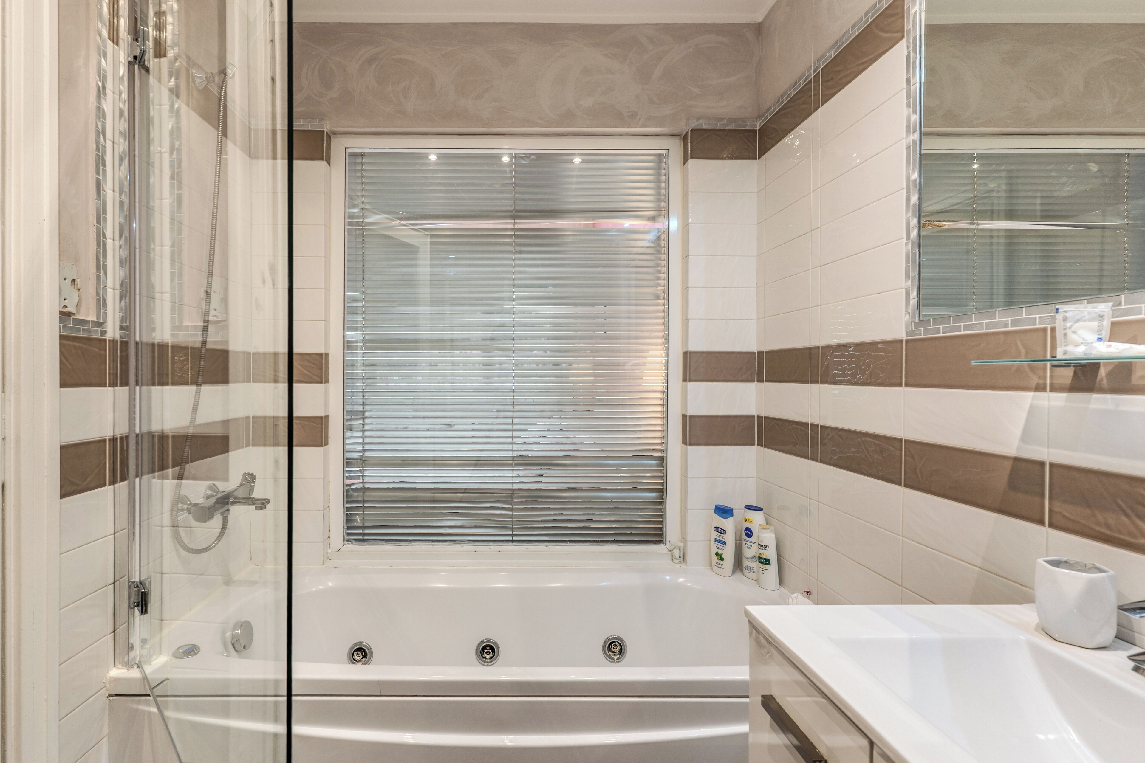 A modern bathroom with a glass-enclosed shower, a bathtub, and a large mirror.