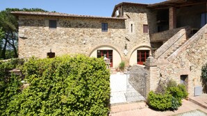 A stone building with a courtyard, arched doorways, and a staircase leading to an upper level.
