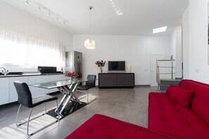 Eine moderne Küche mit Essbereich, einem roten Sofa und einem Fernseher.