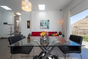 Ein moderner Essbereich mit einem Glastisch, schwarzen Stühlen, einem roten Sofa und einem Stadtbild an der Wand.