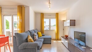 A modern living room with a grey sectional sofa, a small table, and a TV on a wooden cabinet. - Olalla: Villa with private pool in L'Escala (L'Escala)