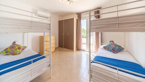 A room with two bunk beds, a wardrobe, and a door leading to an outdoor area. - Olalla: Villa with private pool in L'Escala (L'Escala)
