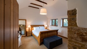 Ein Schlafzimmer mit einem hölzernen Bett, Nachttischlampen, einer Bank und einem großen Fenster.