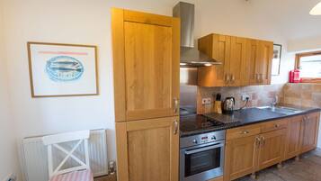 Een keuken met houten kastjes, een roestvrijstalen fornuis en een betegelde spatwand.