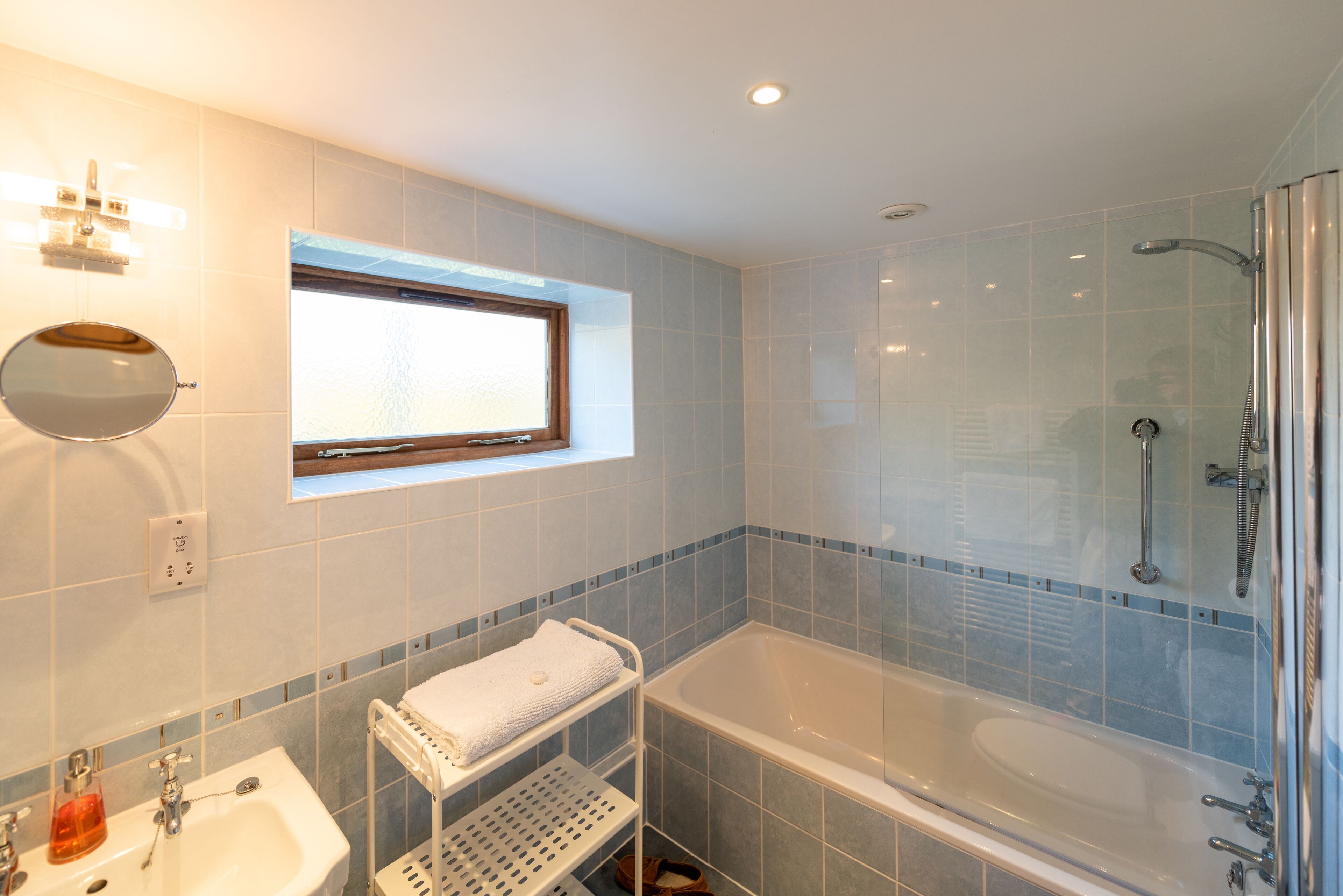 A modern bathroom with a bathtub, a sink, a mirror, and a window.