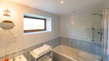 A modern bathroom with a bathtub, a sink, a mirror, and a window.