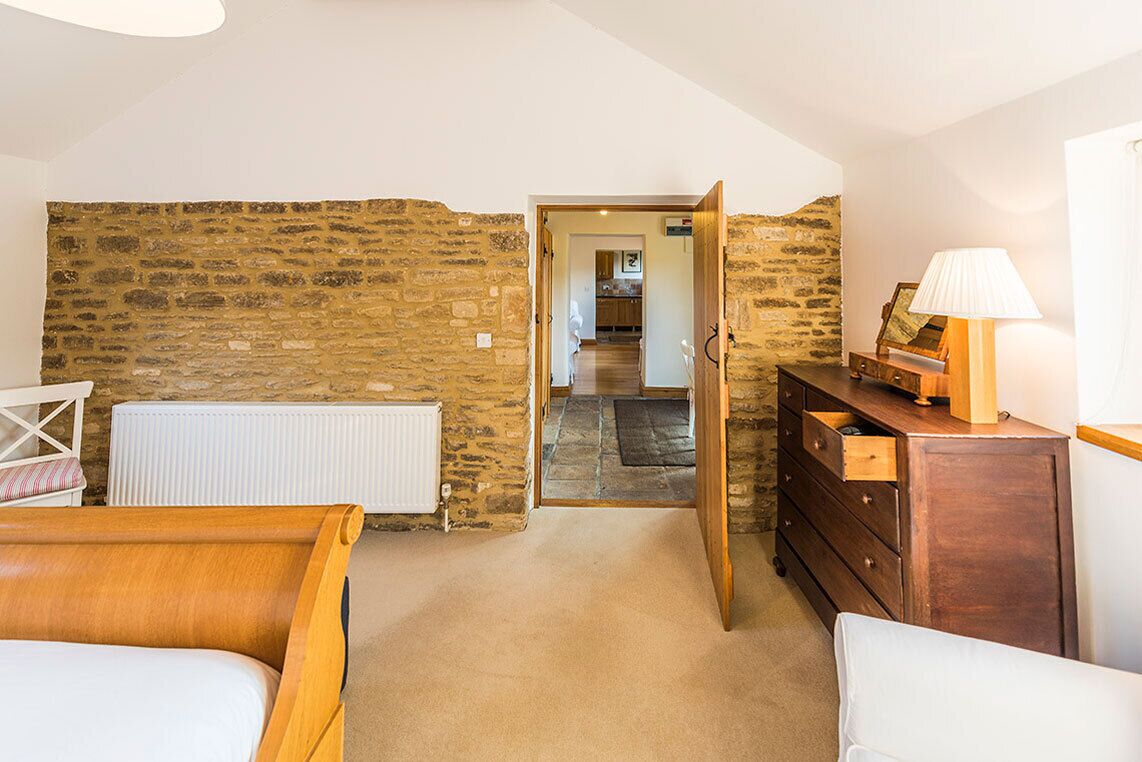 Un dormitorio con pared de piedra, muebles de madera y vista a otra habitación.