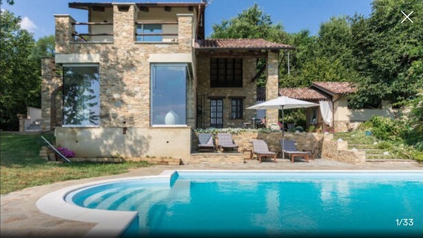 Une maison en pierre avec une piscine, un espace extérieur aménagé et une vue sur la mer.