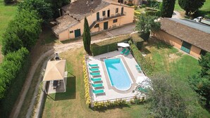 An aerial view of a residential property with a swimming pool, multiple buildings, and surrounding greenery.