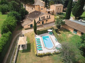 Vista aérea de una propiedad residencial con piscina, varias construcciones y abundante vegetación.
