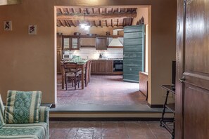 A cozy kitchen with wooden cabinets, a dining area with chairs, and a green door.
