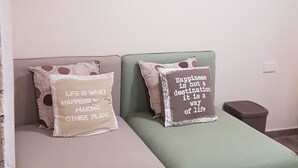 A room with a bed, two pillows, a wall-mounted picture, and a small trash bin.