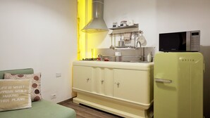 A compact kitchen with a vintage refrigerator, a microwave, and a sink.