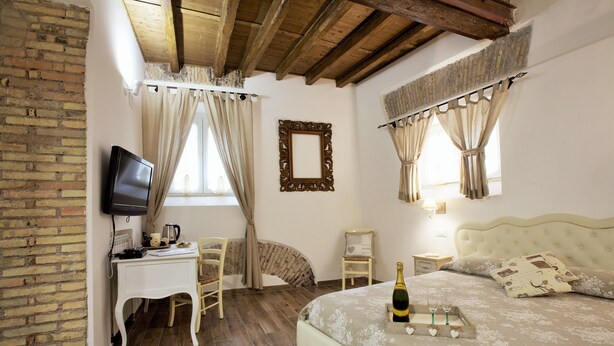 A bedroom with a bed, a desk, a chair, a television, and a window with curtains.