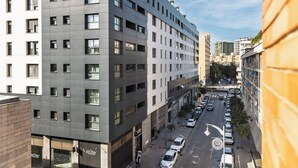 Ein modernes, mehrgeschossiges Gebäude mit einem Raster aus Fenstern und einer Straße davor.