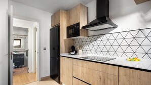 Eine moderne Küche mit Holzausstattung, einer schwarzen Mikrowelle und einer geometrischen Spritzschutzwand.