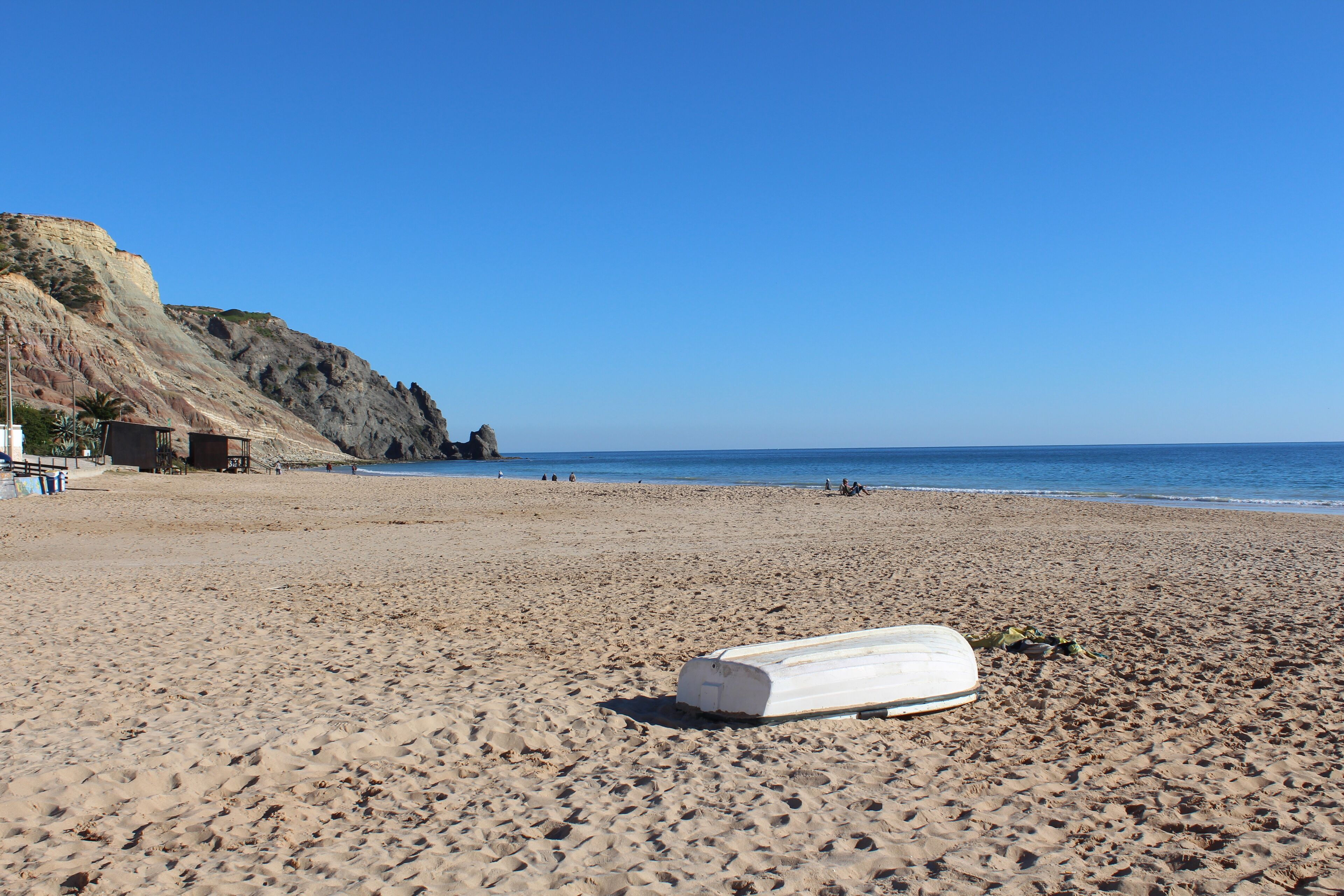 A beach with a lifeguard tower, a rocky cliff, and a lifeguard chair.