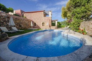 A swimming pool with lounge chairs and umbrellas, surrounded by a stone wall and a building with a tiled roof. - Stone Villa Olga shared pool & seaview, 3bedrooms, BBQ (Astratigos)
