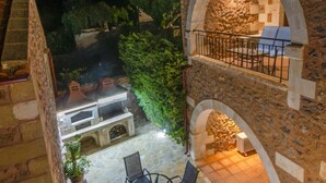 Un pati de pedra amb mobiliari exterior i una paret de pedra.