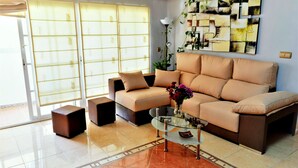 Ein Wohnzimmer mit einem beigefarbenen Sofa, einem Glastisch und einer dekorativen Vase.