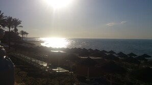 Ein Strand mit Sonnenschirmen und einem Sonnenuntergang.